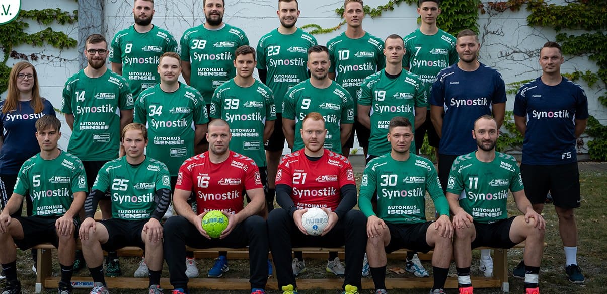 Die 1. Männer in der Saison 2020/21, in grünen Trikots vor einer bewachsenen Wand